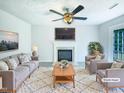 Bright living room featuring fireplace, ceiling fan, neutral walls, and a plush rug at 5828 Brambleton Ave, Raleigh, NC 27610