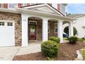 Close-up of the front porch featuring stone details, white pillars, and manicured landscaping at 609 Conover Rd, Durham, NC 27703