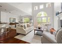Open-concept living room with high ceilings, large windows, hardwood floors, and comfortable seating near a dining area at 97302 Dobbs, Chapel Hill, NC 27517