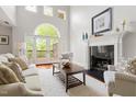 An airy living room with tall windows, a fireplace, hardwood floors, a white rug, and access to an outdoor deck at 97302 Dobbs, Chapel Hill, NC 27517