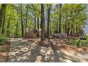 View of long, concrete driveway leading to traditional home surrounded by lush trees and vibrant azaleas at 108 Maplewood Dr, Knightdale, NC 27545