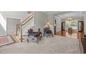 Cozy living room featuring carpeted flooring, staircase, chairs with decorative upholstery, and views into other spaces at 112 Natchez Ct, Cary, NC 27519
