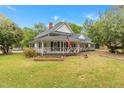 Charming two-story white home with a welcoming wraparound porch, vibrant landscaping, and an American flag at 119 Johnson St, Broadway, NC 27505