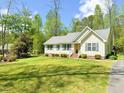 Single-story home featuring a well-manicured lawn, mature trees and a paved driveway at 122 American Rd, Timberlake, NC 27583