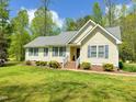 Inviting single-story home showcasing a pristine lawn, mature trees, and stylish blue shutters at 122 American Rd, Timberlake, NC 27583