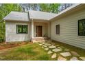 Inviting entryway with stone path, wood door, white siding, and black trim windows at 1368 Ohio Ln, Sanford, NC 27332