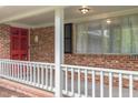 Welcoming front porch with brick siding, white railing, and a bright red front door at 1750 Spring Valley Lake Rd, Henderson, NC 27537