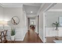 Hallway with wood floors, wainscoting, decorative mirror, and views into living spaces at 2812 Lemnos Dr, Apex, NC 27502