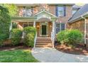 Inviting brick home entrance with white railings, arched entry, and landscaped surroundings at 314 Hogan Woods Cir, Chapel Hill, NC 27516