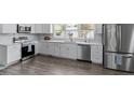 Open kitchen featuring stainless appliances, sleek white cabinetry and hardwood floors at 3713 Arrowwood Dr, Raleigh, NC 27604