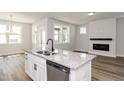 Open-concept kitchen with island, stainless steel sink, and a view of the fireplace and living area at 528 Folk Song Way, Wendell, NC 27591