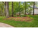 Well-manicured front yard with mature trees, shrubbery, and planted flower beds at 7709 Oakmont Pl, Raleigh, NC 27615