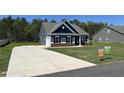 New home with a long driveway, attached garage, well-kept lawn, and visible signage for available properties at 95 Knoll Way, Sanford, NC 27332