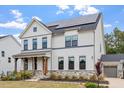 Stylish two-story home featuring white brick, dark trim, solar panels, and a charming covered porch at 956 The Parks Dr, Pittsboro, NC 27312