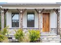 Close-up of a charming front porch with decorative stone, wood pillars, lighting, and a modern front door at 956 The Parks Dr, Pittsboro, NC 27312