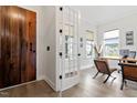Bright home office with hardwood floors, a modern desk, executive chairs, and a unique wooden door at 956 The Parks Dr, Pittsboro, NC 27312