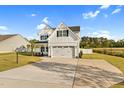 Two-story white farmhouse exterior featuring a two-car garage, wide driveway and manicured front lawn at 105 Blooms Way, Kenly, NC 27542