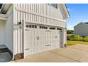 White two-car garage door with black hardware on a white farmhouse-style home at 105 Blooms Way, Kenly, NC 27542