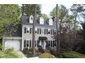 Charming two-story home with a light gray exterior, blue door, dormer windows, and lush landscaping at 117 Vicksburg Dr, Cary, NC 27513