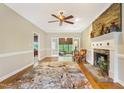 Bright living room with hardwood floors, a stone fireplace, ceiling fan, and glass doors leading to another room at 117 Vicksburg Dr, Cary, NC 27513