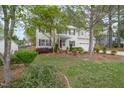 Beautiful home exterior with lush landscaping, mature trees, and a well-maintained lawn at 1208 Lexington Farm Rd, Apex, NC 27502