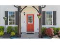 Inviting front entrance with a vibrant red door, lush landscaping, and decorative hanging plants at 166 Yellow Jacket Rdg, Clayton, NC 27520