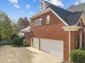 A brick house featuring a three-car garage, basketball hoop, and mature landscaping at 204 Oxford Mill Ct, Cary, NC 27518