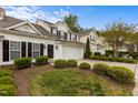 Inviting townhouse featuring a two-car garage, well-manicured lawn, and striking black shutters at 292 Joshua Glen Ln, Cary, NC 27519