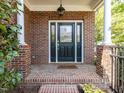 Elegant front door with glass panels, brick surround, and 'Home Sweet Home' welcome mat on a brick porch at 3608 Burwell Rollins Cir, Raleigh, NC 27612