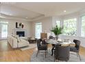 Bright living room featuring hardwood floors, a fireplace, large windows, a dining area, and neutral decor at 3608 Burwell Rollins Cir, Raleigh, NC 27612