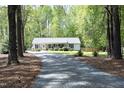 Idyllic exterior view of a home with a long driveway, lush trees, and a well-maintained lawn at 38 Maple Cir, Pittsboro, NC 27312