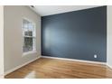 Bright bedroom features hardwood floors, a large window, and a stylish accent wall at 3811 Yates Mill Trail, Raleigh, NC 27606