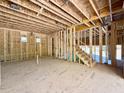 Unfinished living room with exposed ceiling joists, stud walls and staircase at 3817 Coach Lantern Ave, Wake Forest, NC 27587