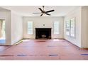 Bright living room with dark fireplace mantel, ceiling fan, and large windows bringing in plenty of light at 3817 Coach Lantern Ave, Wake Forest, NC 27587