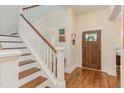 Elegant foyer with hardwood floors, staircase, and view of front door and colorful artwork at 43 Turtle Point Bnd, Chapel Hill, NC 27516
