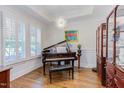 Elegant living room featuring hardwood floors, tray ceiling, piano, and a charming china cabinet at 43 Turtle Point Bnd, Chapel Hill, NC 27516