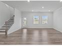 Bright living room with wood-look flooring, a staircase with decorative iron railing, and abundant natural light at 5016 Tura St, Raleigh, NC 27610