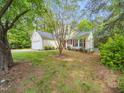 Side view of a charming two-story home with red shutters and a well-maintained lawn with mature trees at 5504 Cumberland Plain Dr, Raleigh, NC 27616