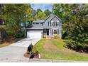 Charming gray home with white trim, lush landscaping, and a two-car garage on a sunny day at 7 Wythebrook Ln, Durham, NC 27713