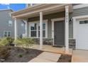 Inviting front porch with stone accents and a contemporary gray front door at 7205 Tillage Rd, Mebane, NC 27302