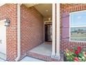 View of the front entry showing red brick, manicured rose garden, and front door at 8 Pal Ct, Benson, NC 27504