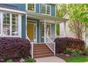 Inviting front porch with brick steps, white railings, and a bright yellow front door at 8005 Somerdale Dr, Durham, NC 27713