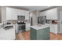 Bright kitchen featuring white cabinets, stainless steel appliances, and a green center island at 8005 Somerdale Dr, Durham, NC 27713