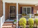 Inviting front porch with brick steps, white railings, and decorative hanging flower baskets at 8212 Duck Creek Dr, Raleigh, NC 27616