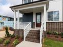 Inviting front porch with brick accents and white railing, leading to a stylish entryway at 10 Relaxing Way, Pittsboro, NC 27312