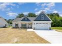 Charming home featuring a two-car garage, stone accents and a manicured lawn under a bright blue sky at 1000 Peedin Rd, Selma, NC 27576