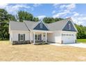 Charming single-Gathering home featuring a covered front porch, landscaped yard, and attached garage at 1000 Peedin Rd, Selma, NC 27576