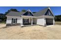 Home exterior showcasing stone accents, covered entry, white siding, and a two-car garage at 1000 Peedin Rd, Selma, NC 27576