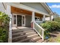 Inviting front porch with wood ceiling, white columns and railing, and security system at 104 E Wilson St, Mebane, NC 27302