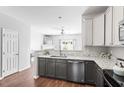 Bright kitchen featuring gray cabinets, granite countertops, stainless steel appliances, and an open view to the living area at 11210 Lofty Heights Pl, Raleigh, NC 27614